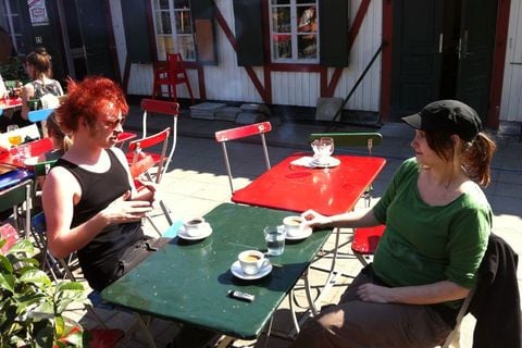 Two people sitting at tables at an outdoor cafe.