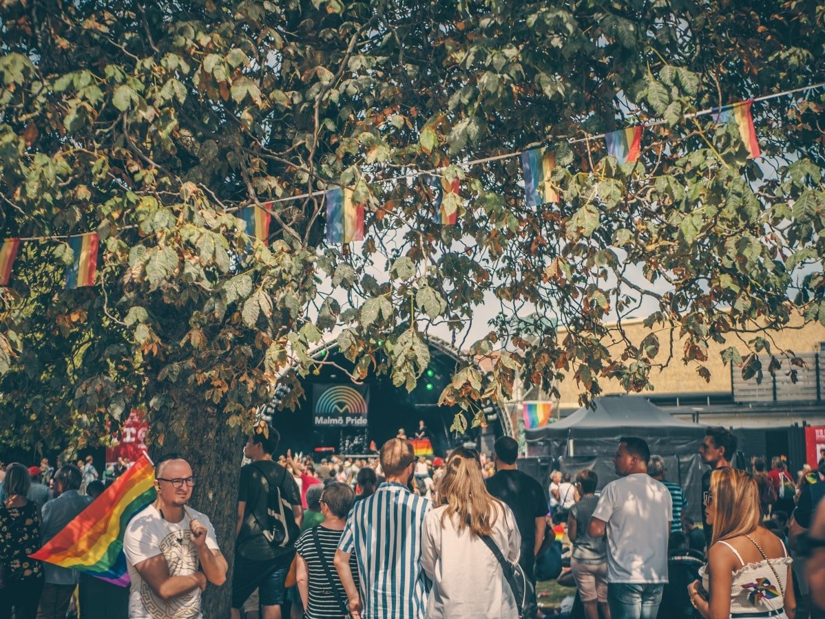 A group of people standing under a tree at a festival.