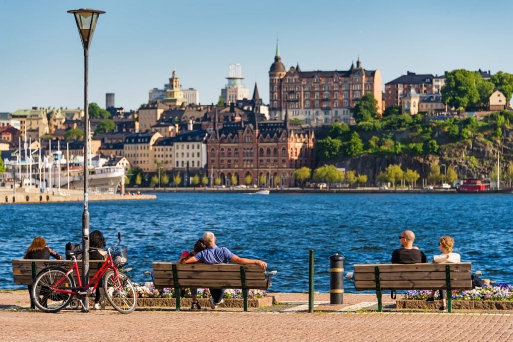 A group of people sitting on a bench near a body of water.