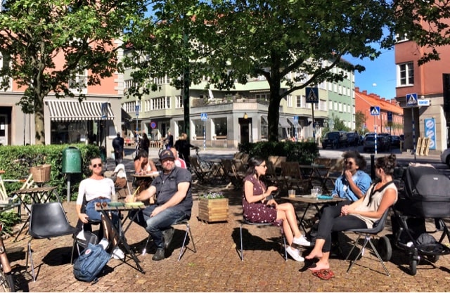 A group of people sitting at tables in a city.