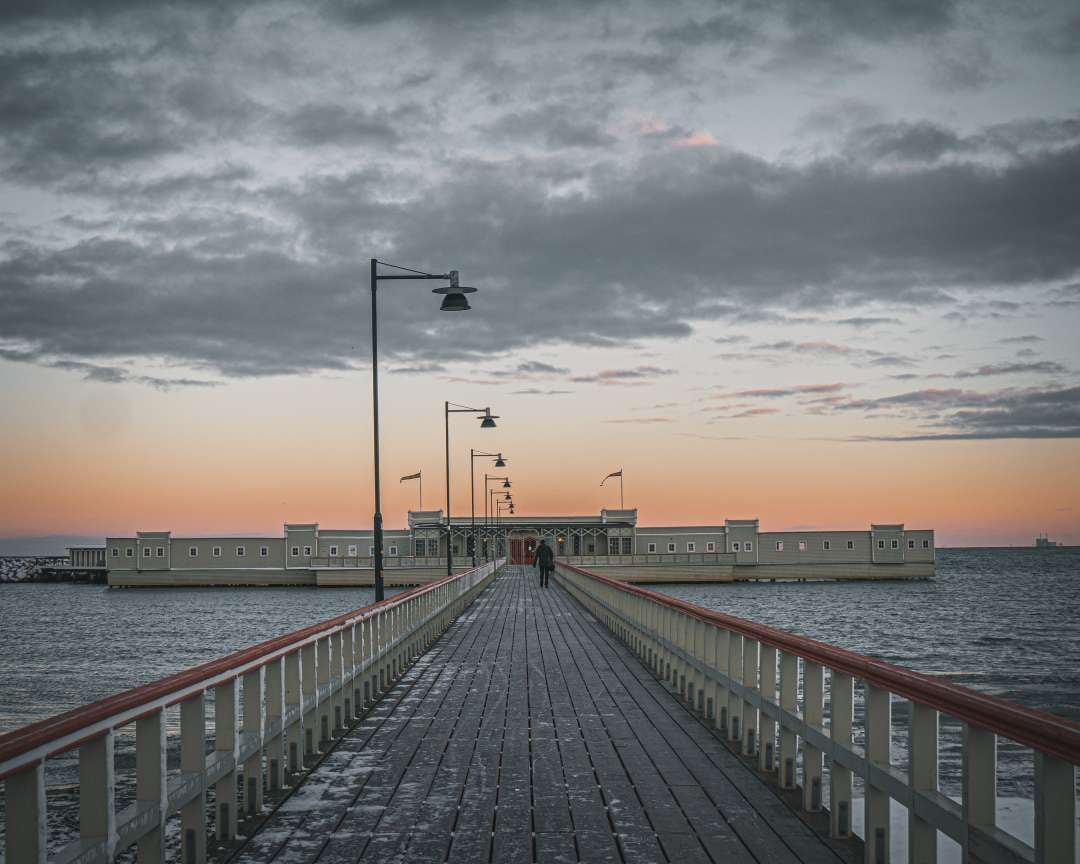 A wooden pier leading to the water at sunset.