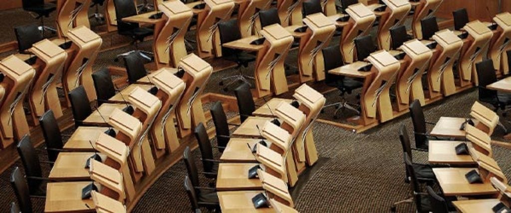 The scottish parliament has a large number of wooden desks.