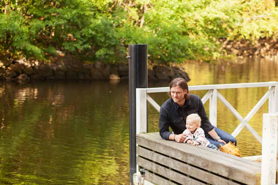 A man and a child sitting on a dock near a lake.