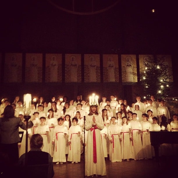 A group of people in Swedish "lucia robes" standing in front of a christmas tree.
