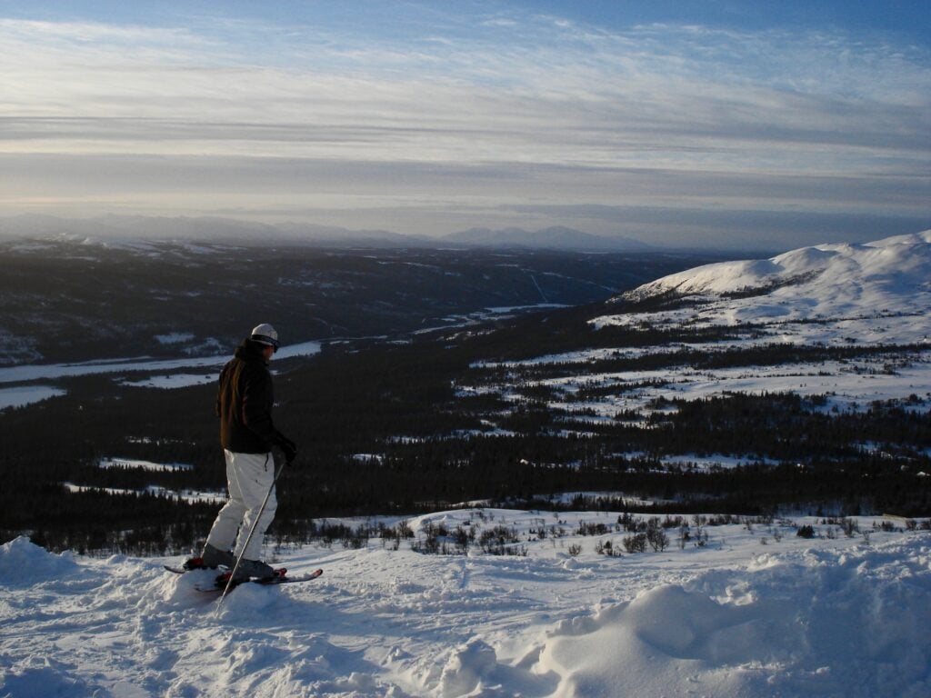 A person standing on top of a snow covered hill.