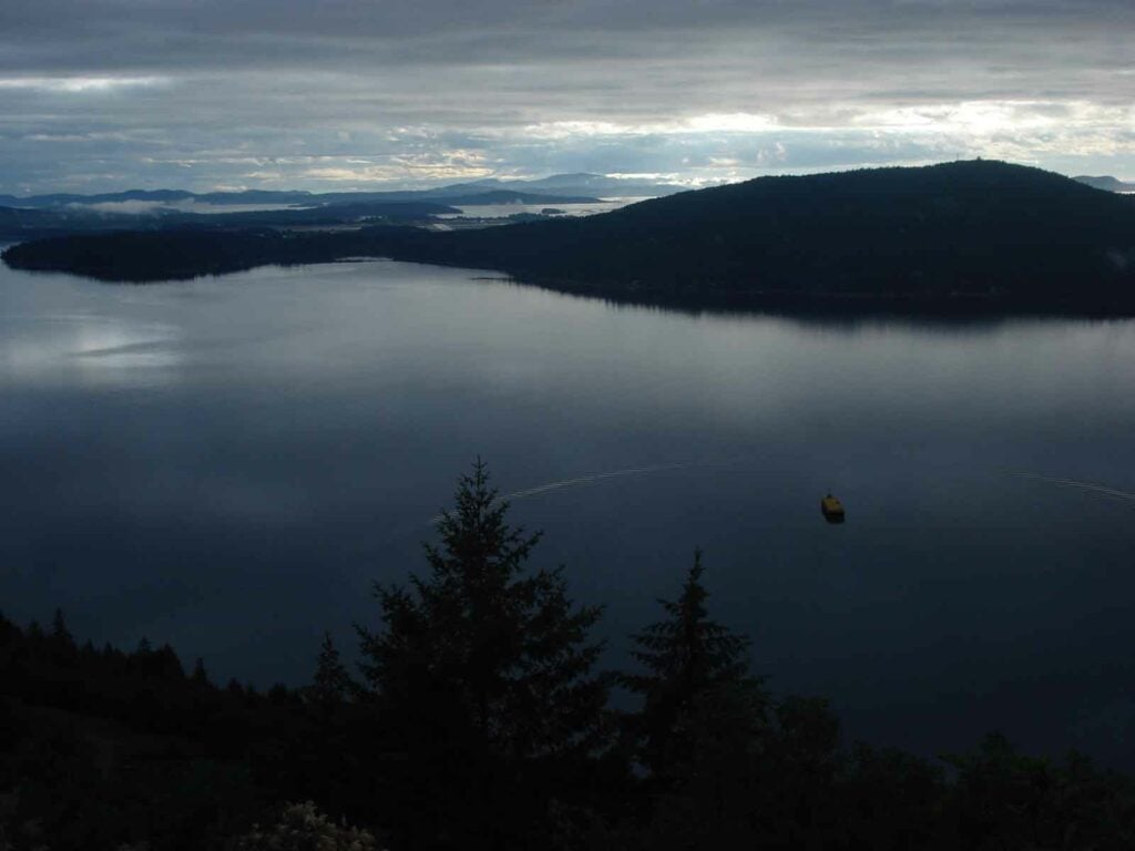 A boat floating in a body of water under a cloudy sky.